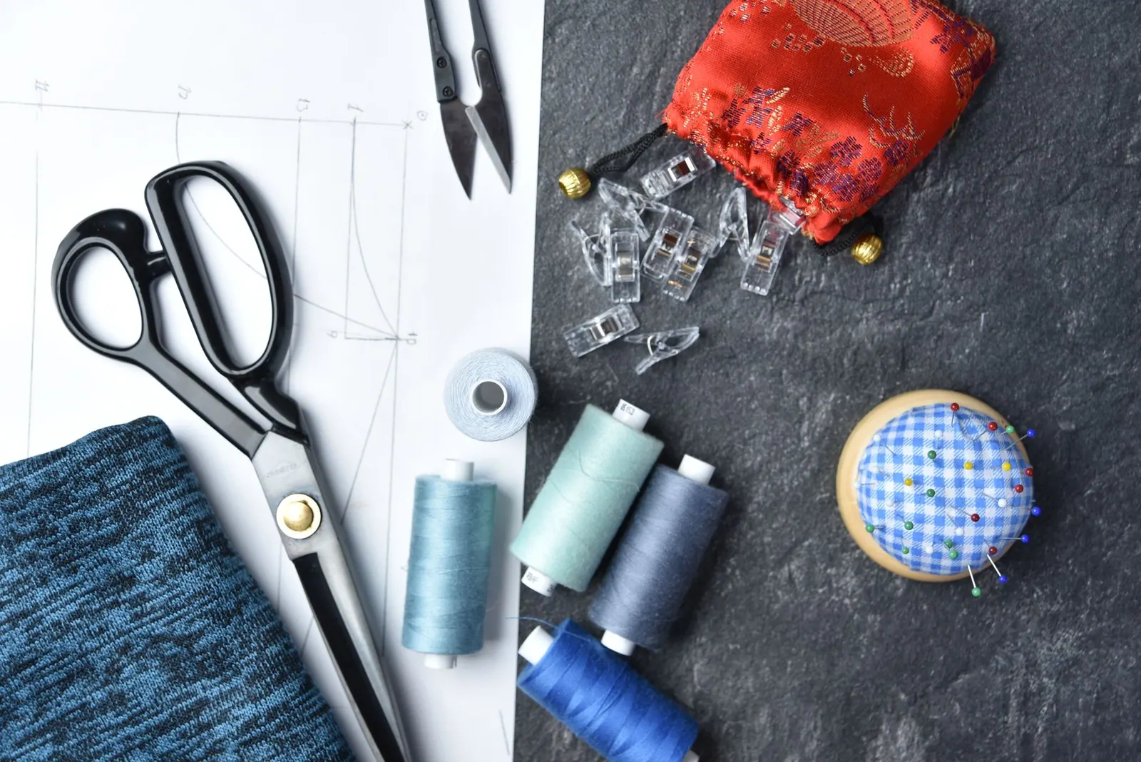 Flat lay of sewing supplies and tools, featuring threads, scissors, and fabric.