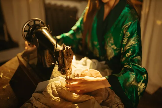 A fashion designer sewing with a vintage machine in a textile studio.