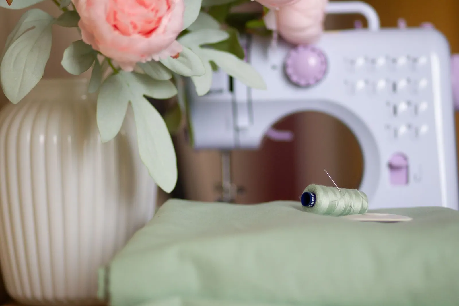 Chic sewing setup with a vintage machine, flowers, and thread.